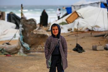 Un niño intenta mantenerse caliente con ropa de invierno mientras las tormentas azotan Gaza.