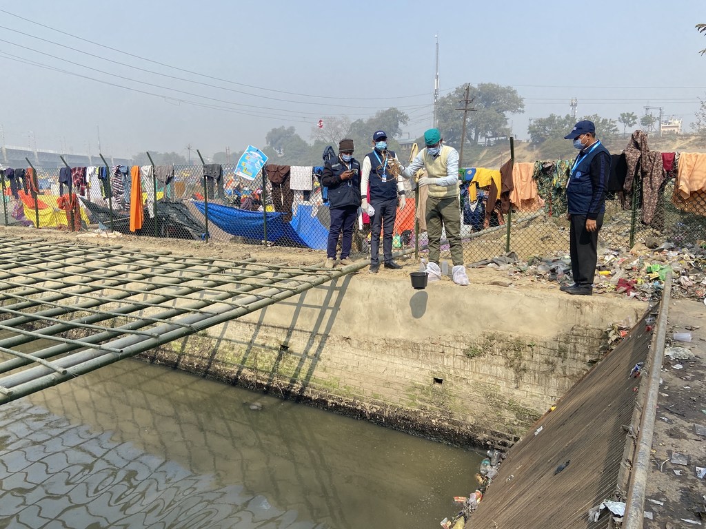 भारत में कुंभ मेले के दौरान डब्ल्यूएचओ के अधिकारी एक पंपिंग स्टेशन पर सीवेज के नमूने एकत्र करते हैं।