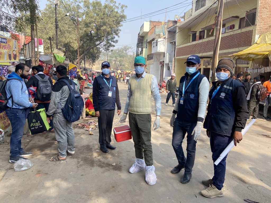 कुंभ मेले में पोलियो निगरानी अभियान के दौरान सुरक्षात्मक गियर पहने डब्ल्यूएचओ के जवानों की एक टीम भारत के लखनऊ की एक सड़क पर खड़ी है।
