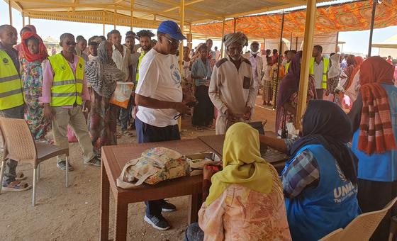 विश्व खाद्य कार्यक्रम (WFP) के कर्मचारी, सूडान में विस्थापितों के लिए स्थापित एक शिविर में खाद्य सामग्री वितरित करते हुए.