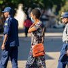 在津巴布韦首都哈拉雷街头，一名佩戴防疫口罩的妇女从几位警员身边走过。（资料图片）
