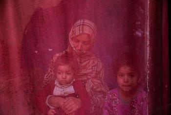 امرأة أصبحت عاطلة عن العمل بسبب مراسيم طالبان تجلس في منزلها مع ابنتيها.