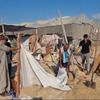 Watu waliokimbia makazi yao wakitafuta kupitia vifusi vya kambi ya muda iliyoharibiwa huko Al Mawasi, Ukanda wa Gaza, baada ya shambulio la anga.