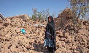 Uma mulher está entre os escombros de sua casa destruída na província de Herat, no Afeganistão