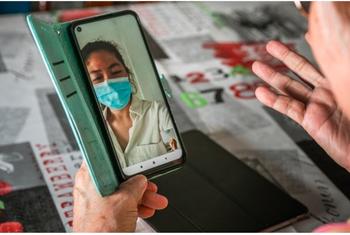 新加坡一名妇女在家中使用数字设备连接社区医院看诊。