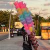 Um vendedor ambulante no México vende algodão-doce e maçãs do amor coloridas em uma grande barraca na calçada ao entardecer.