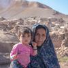 Nazook amembeba mtoto wake wa miezi 10, Fatima, mbele ya kijiji kilichoharibiwa na matetemeko ya ardhi huko Herat, Afghanistan.