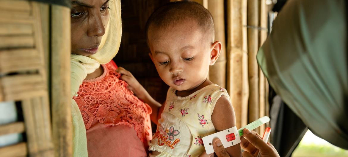 متطوعة في مجال التغذية تُقيم حالة طفل من الروهينجا في مخيمات كوكس بازار للاجئين في بنغلاديش.