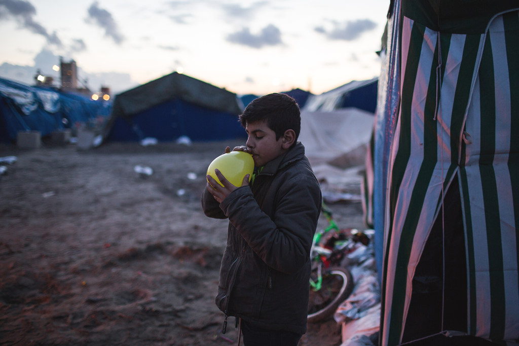 Un niño refugiado sirio infla un globo amarillo en un campamento de tiendas de campaña improvisado en Calais, Francia.