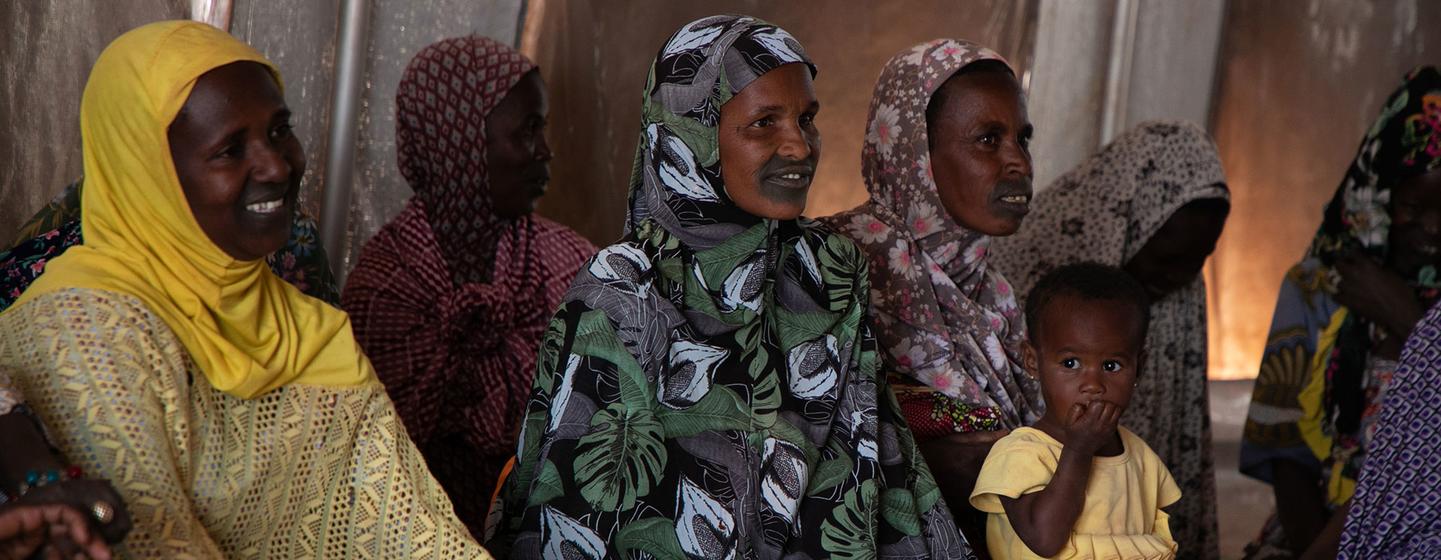 Un grupo de mujeres, entre ellas una con un niño pequeño, escucha a una comadrona durante una sesión de sensibilización sobre salud en un campamento de desplazados en Mali.