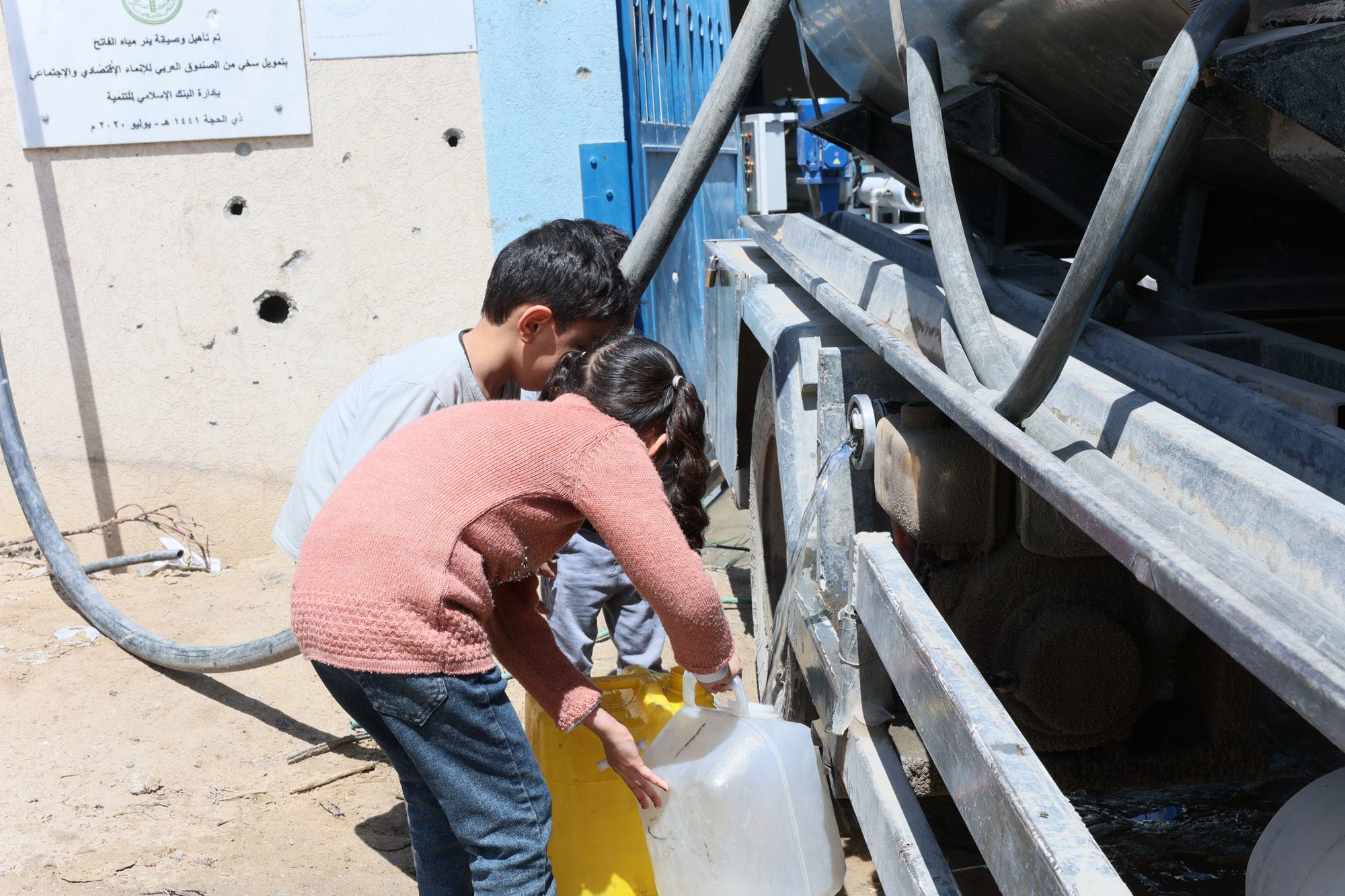 Deux enfants de Gaza récupèrent de l'eau dans un camion (archive).