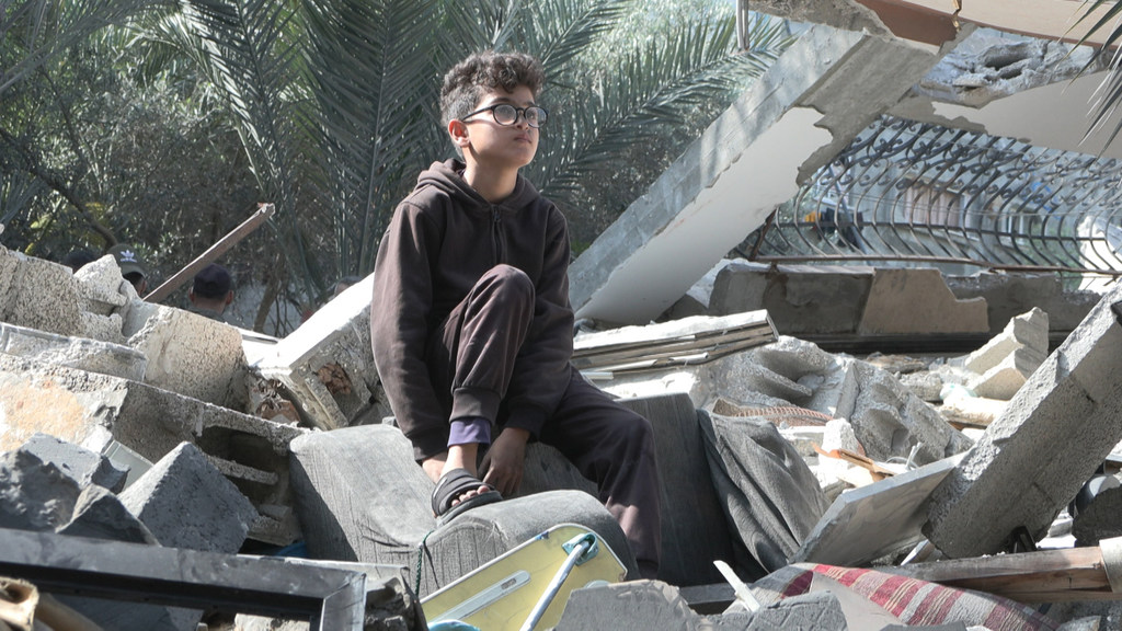 Un niño palestino se sienta sobre las ruinas de su casa en Gaza, destruida por los ataques aéreos israelíes de agosto de 2022.