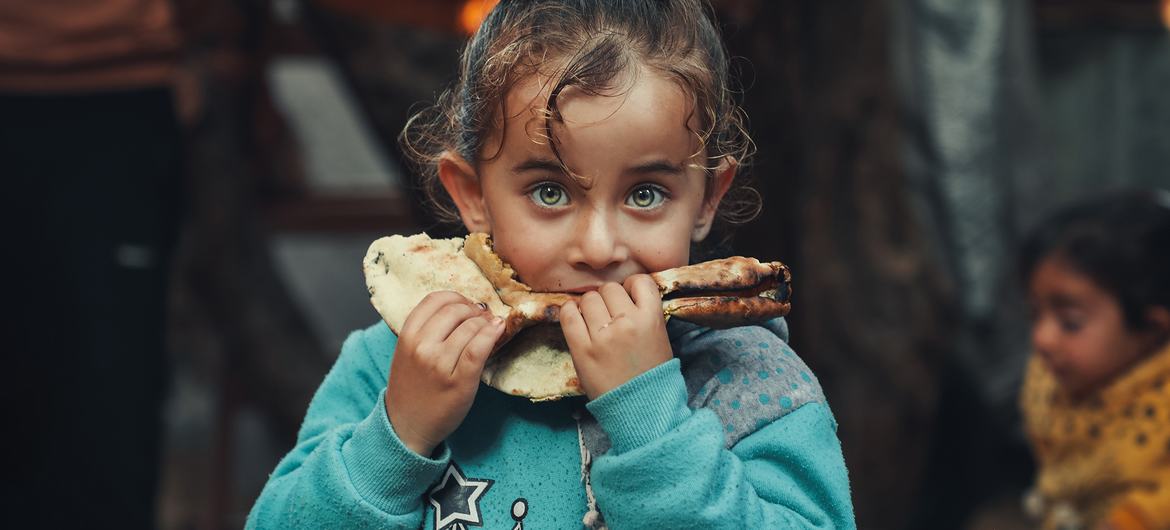 طفلة فلسطينية في غزة تأكل خبزا، أعدته والدتها بمواد غذائية اشترتها بدعم من برنامج الأغذية العالمي.