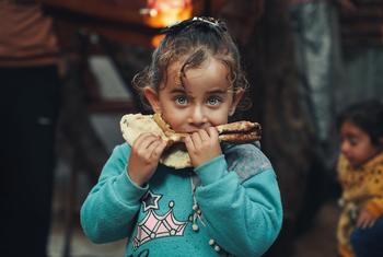 طفلة فلسطينية في غزة تأكل خبزا، أعدته والدتها بمواد غذائية اشترتها بدعم من برنامج الأغذية العالمي.