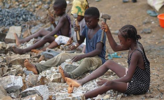 Kwenye machimbo ya mawe katika jamii ya Gombu huko Kenema, Sierra Leone, Adama (kulia, akiwa amevaa gauni jeusi lenye madoa meupe), mwenye umri wa miaka 12, pamoja na marafiki zake hufanya kazi pamoja na watu wazima, wakivunja vipande vikubwa vya granite…