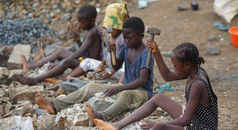 Kwenye machimbo ya mawe katika jamii ya Gombu huko Kenema, Sierra Leone, Adama (kulia, akiwa amevaa gauni jeusi lenye madoa meupe), mwenye umri wa miaka 12, pamoja na marafiki zake hufanya kazi pamoja na watu wazima, wakivunja vipande vikubwa vya granite…