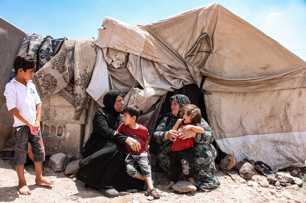 Una familia de refugiados sirios se sienta a las afueras de su campamento de tiendas de campaña en Oriente Medio.