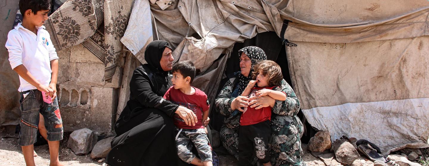 Une famille de réfugiés syriens est assise devant son camp de tentes au Moyen-Orient.