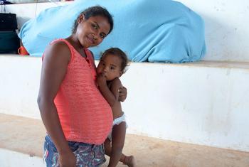 Una mujer brasileña embarazada carga a su hija.