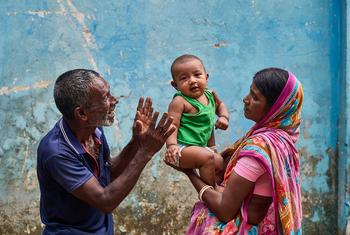 A mother and grandparent share joy with a baby while waiting at the Kolagaon Community Clinic in Tahirpur, Bangladesh.