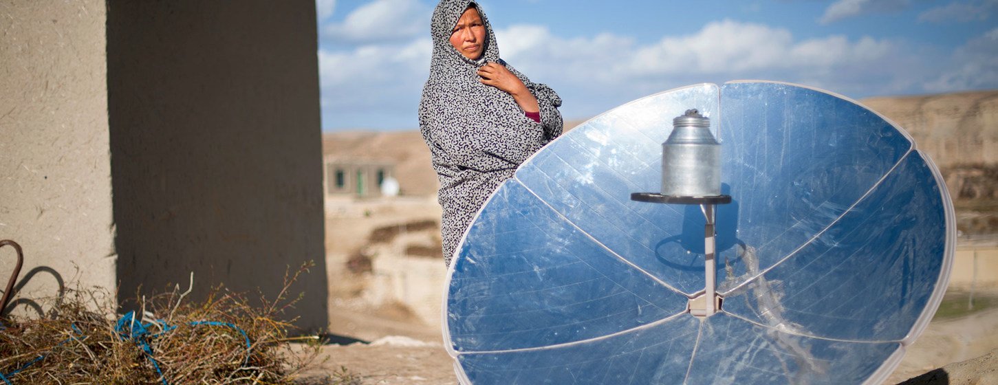 A woman in Afghanistan stands next to a solar cooking disc. (file)