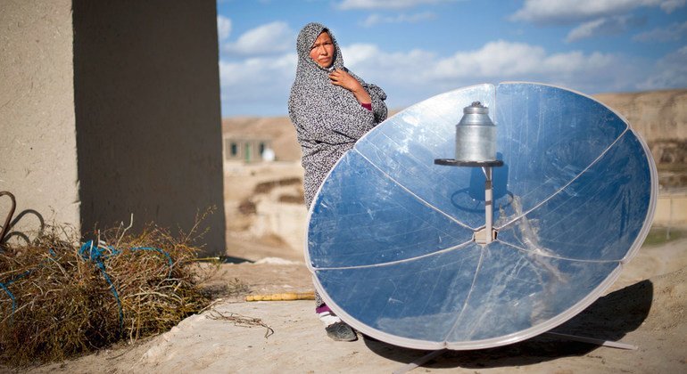 Женщина в Афганистане стоит рядом с диском для приготовления пищи на солнечных батареях. 