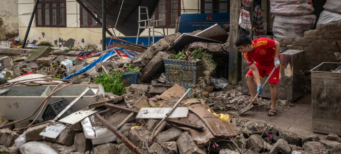 A young Vietnamese man cleans up the rubble of his home after Typhoon Yagi swept through Quang Ninh Province.