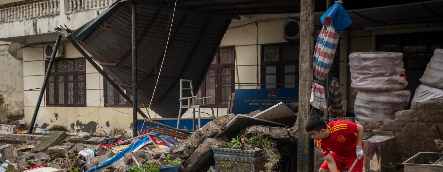 A young Vietnamese man cleans up debris at his home after Typhoon Yagi swept through Quang Ninh province.