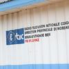 Nembo na ishara ya RTNC, Radio Television Nationale Congolaise, Direction Provinciale du Nord-Kivu, Sous-Station de Beni, FM 91.0 MHz, zinaonyeshwa kwenye ukuta wa bati.