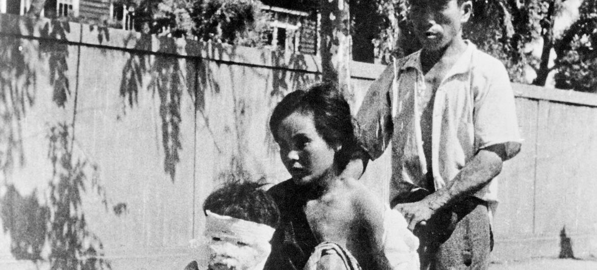 Picha nyeusi na nyeupe ya kihistoria ya raia watatu wa Japani, ambao huenda wamenusurika bomu la atomiki la Hiroshima, ambao wamepokea huduma ya matibabu.