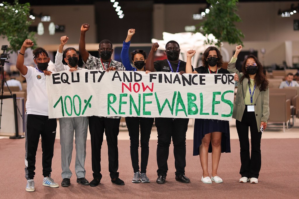 Un grupo de activistas sostiene una pancarta con el lema "Equidad y financiación para el 100% de energías renovables ahora" en la conferencia COP28 en Dubái.