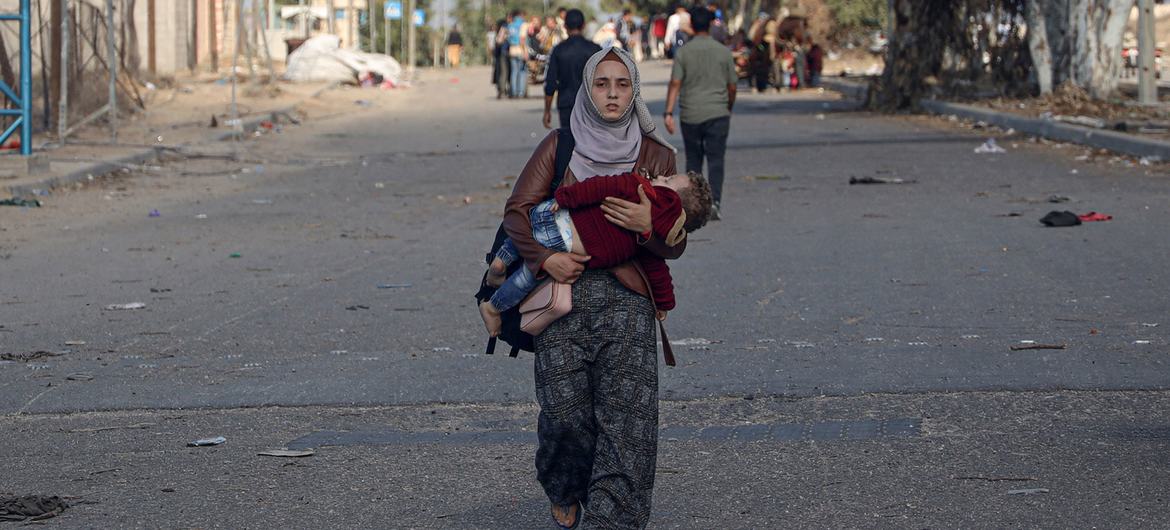 ایک ماں اپنے بچے کے ساتھ محفوظ پناہ گاہ کی تلاش میں پیدل جنوبی غزہ کی طرف جا رہی ہے۔