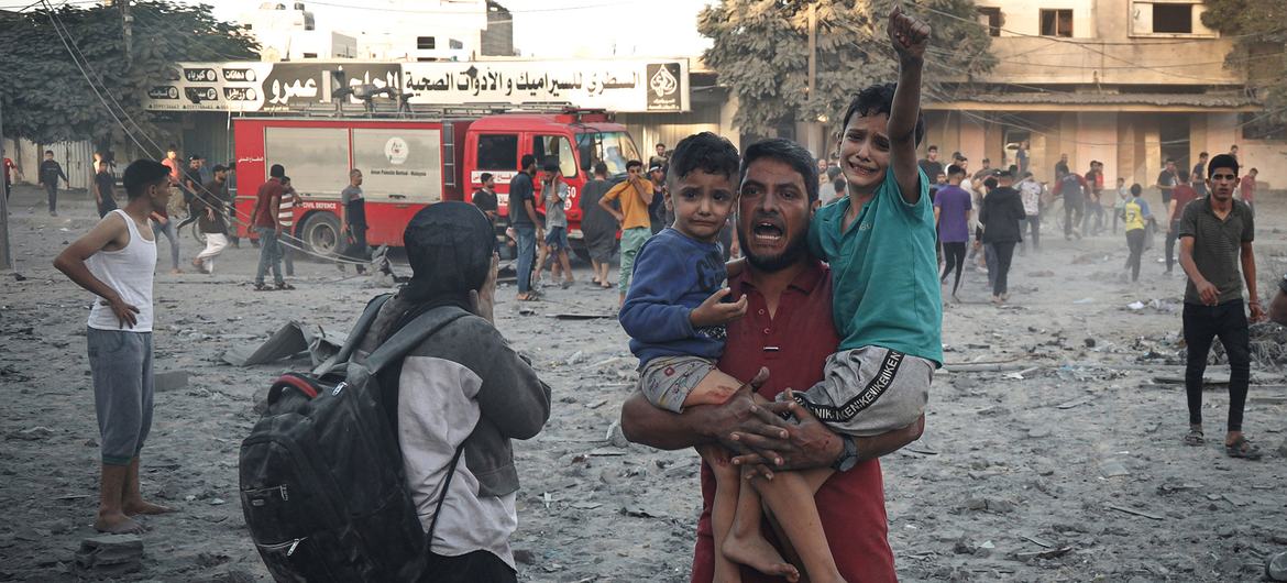 اسرائیلی بمباری سے بچنے کے لیے غزہ کے شہر رفح میں ایک باپ اپنے دو بچوں کو اٹھائے کسی محفوظ پناہ گاہ کی تلاش میں بھاگ رہا ہے۔