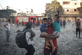 أب يحمل طفليه أثناء فرارهم من غارة جوية على مدينة رفح في قطاع غزة.