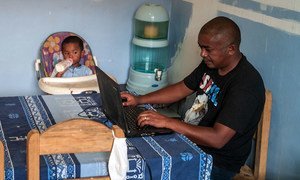 A father takes care of his young child while working from home in Madagascar.