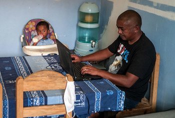 A father takes care of his young child while working from home in Madagascar.
