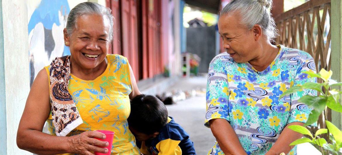 Two elderly people in Indonesia play with a child.