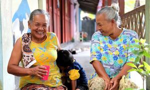 Two elderly people in Indonesia play with a child.