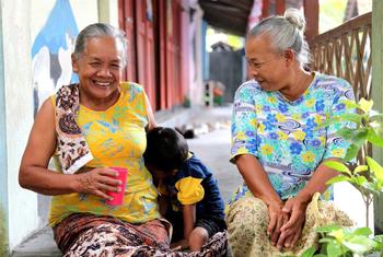 Two elderly people in Indonesia play with a child.