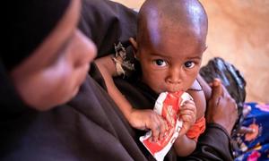A child is held by his mother as he feeds on a sachet of ready-to-use therapeutic food in Somalia.