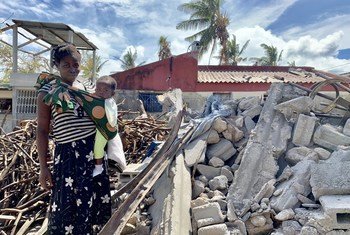 Uma mulher afetada pelo ciclone Idai em Moçambique segura seu bebê em meio aos escombros de um prédio destruído em 2019.