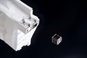 一颗 CubeSat 卫星从更大的白色航天器结构中部署，背景是漆黑的太空。