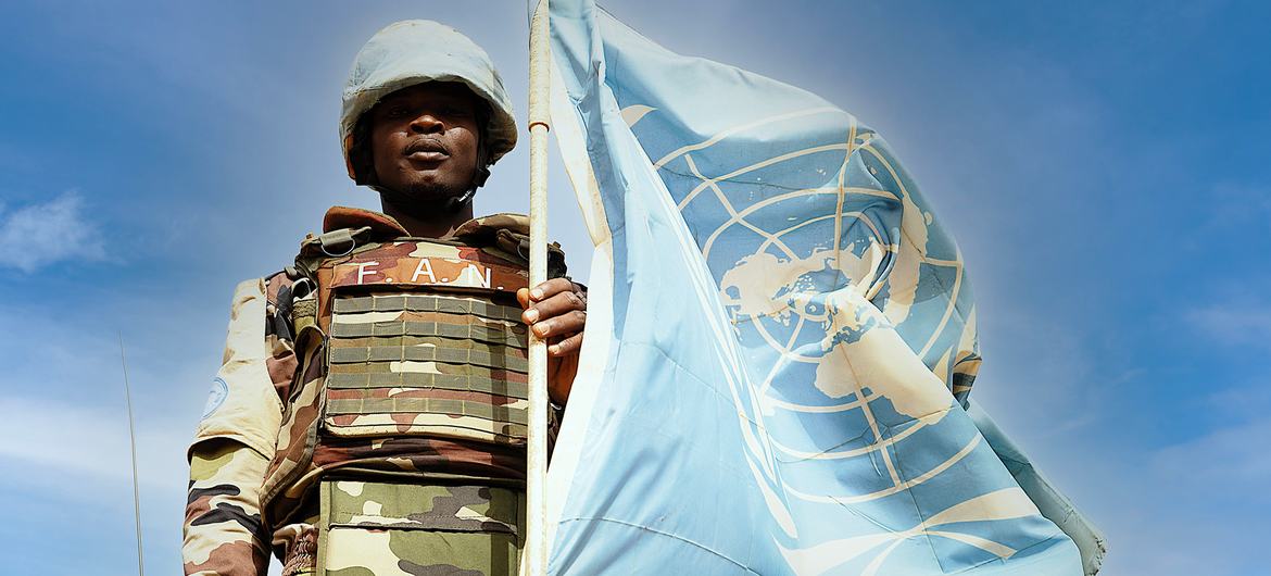 Uma força de paz da ONU do Níger posa ao lado da bandeira das Nações Unidas em Ménaka, no sudeste do Mali.