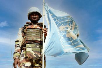 Un Casque bleu nigérien pose devant le drapeau des Nations Unies à Ménaka, dans le sud-est du Mali.
