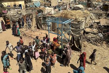 An aerial view of children and their families standing near temporary shelters at the Khamsa Dagiga site for displaced people in Zelingei Town, Central Darfur, Sudan