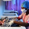 科特迪瓦南部城市阿比让市郊，一家医院的护士戴着口罩和手套照顾新生儿。