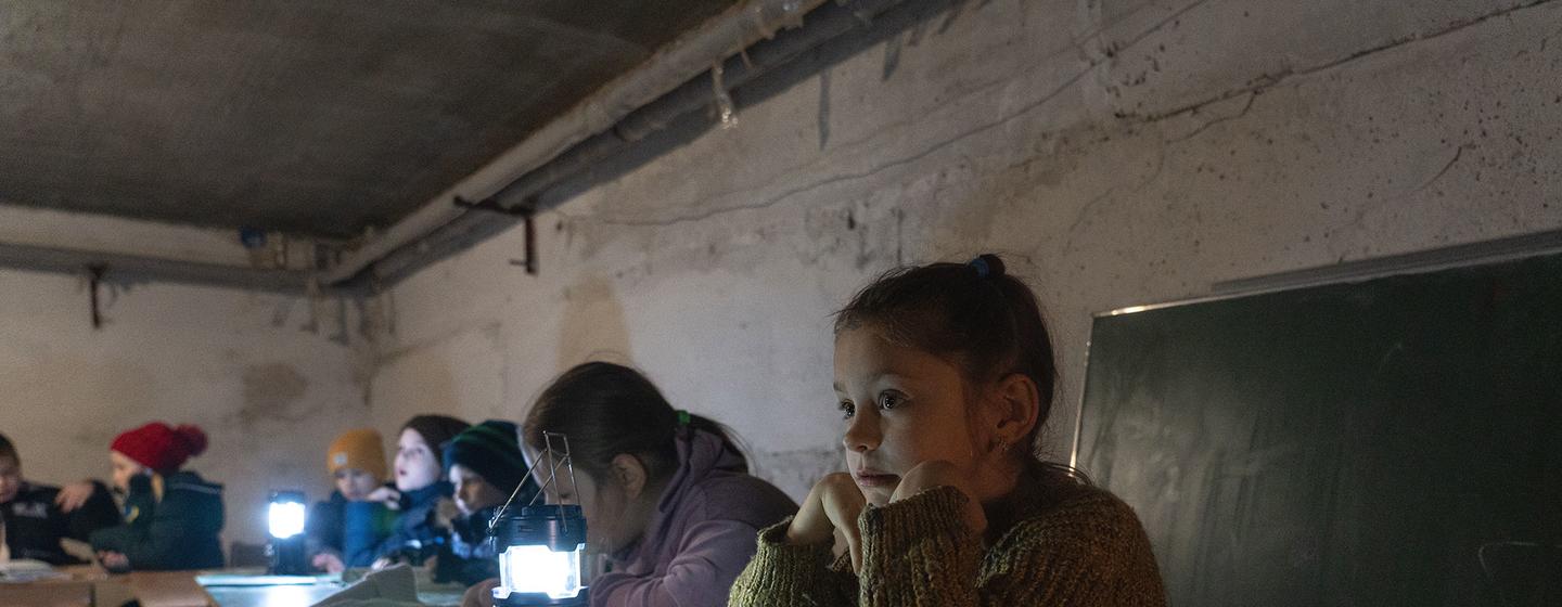 Des enfants de Borodianka, en Ukraine, étudient à la lumière d'une lampe dans un abri