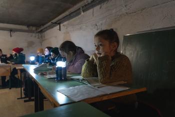 Des enfants de Borodianka, en Ukraine, étudient à la lumière d'une lampe dans un abri
