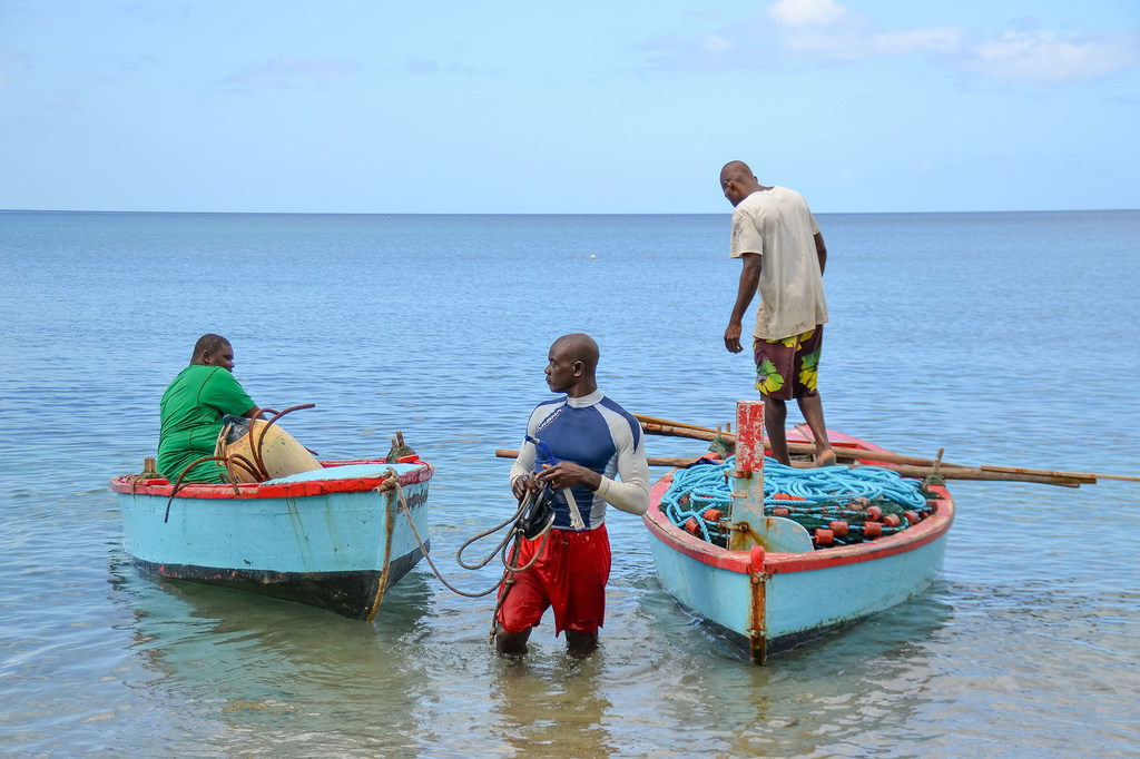 Wavuvi watatu huko Grenada wakiwa na boti zao majini.
