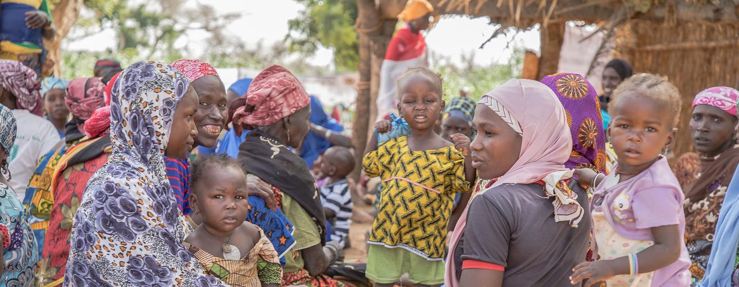 Des femmes et des enfants d'une communauté du Niger sont assis par terre, à l'extérieur, lors d'un événement du PAM .